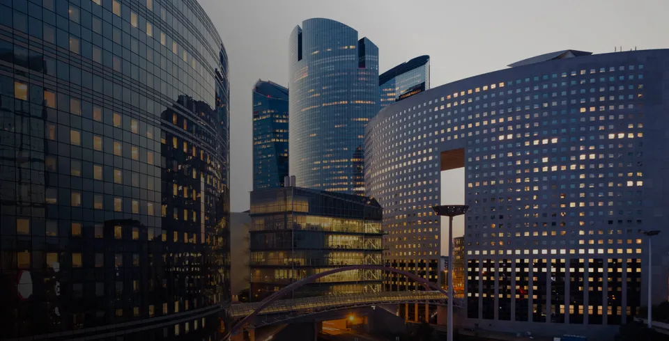Glass office towers with aluminium curtain-wall façades at dusk.